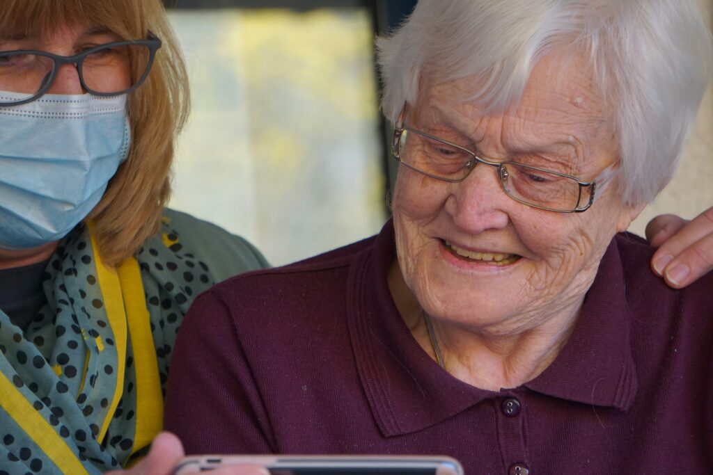 old lady being shown something on phone in care home
