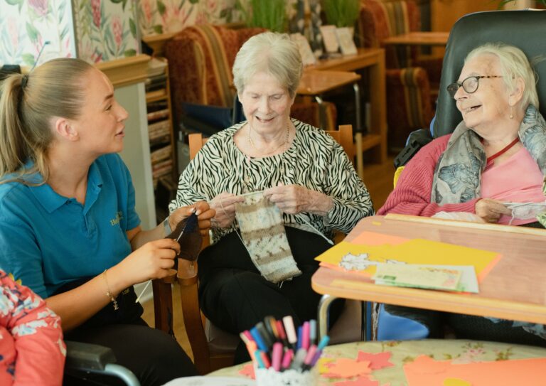 Pair of old women in a care home being looked after by worker